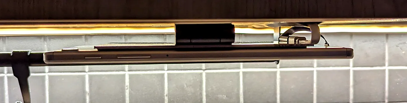 Tablet flipped up, side view: hinge between cabinet floor and tablet, cable loop on the right